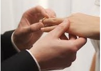 Close-up of a groom placing a wedding ring on his bride's finger